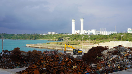 industrial landscape on a tropical island. scrap metal dump on the background of a large factory on the ocean. Ecological problem of humanity. ocean pollution