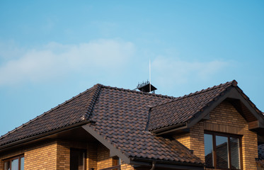Brown natural tile roof. Modern types of roofing materials. Roof of the house, Natural roof tile against the blue sky. Building.