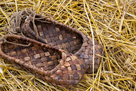 Bast shoes on the straw, traditional wicker shoes of ancient Russia. Close up shot