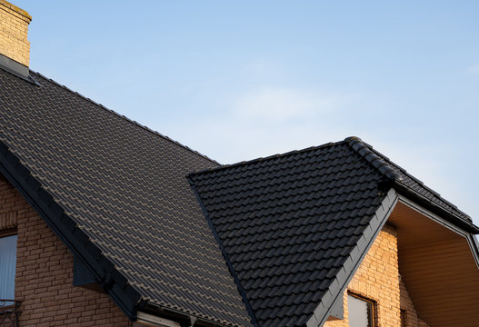 Brown metal tile roof. Roof metal sheets. Modern types of roofing materials. Roof of the house, metal roof tile against the blue sky. Building.