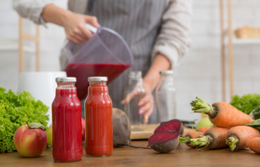 Woman pouring deox red detox cocktail into bottles