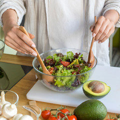 Young unrecognizable woman preparing vegetable salad with avocado