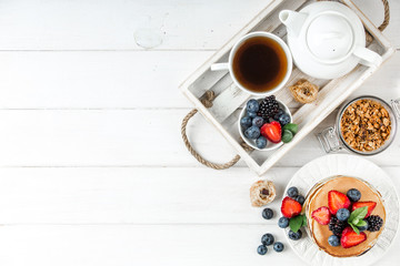 Healthy breakfast with american pancake, granola, fruits, berries on white background.
