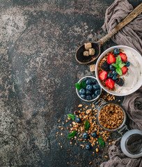 Healthy breakfast with granola, yogurt, fruits, berries on dark metal background. Summer homemade breakfast.