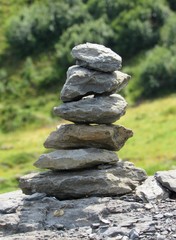 A rock cairn created on a hiking trail in Switzerland rests peacefully on a boulder.