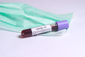 Obraz premium Close Up Photo, Simple Conceptual, Glass Blood Covid-19 Test tube, without result, above N95 Surgical Mask 