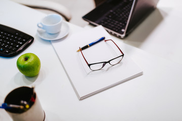 Glasses, face mask, gloves, hand sanitizer and apple on the office desk. COVID - 19 virus protection