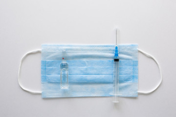 Antiviral medical mask for protection against COVID-19. Medical respiratory bandage face on white background with syringe