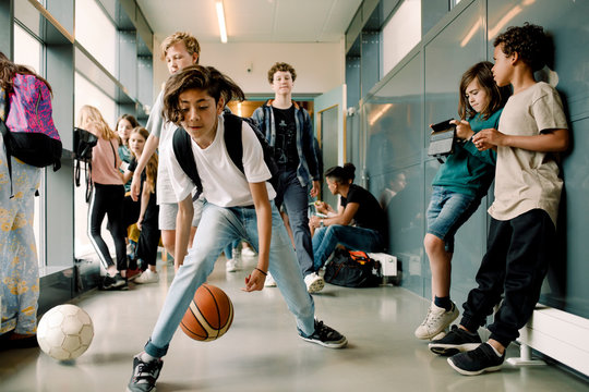 Boy playing with basketball during lunch break in school corridor