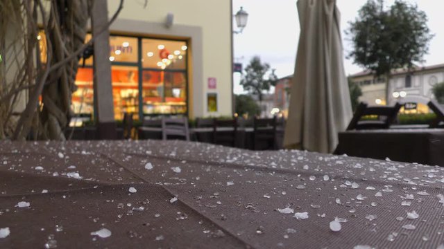 Sudden bad weather. Hail falls on the table of a street cafe covered with a tablecloth.
