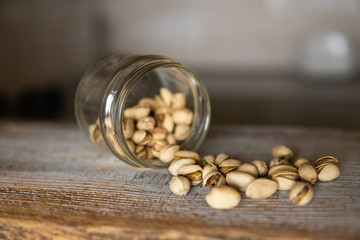Pistachios scattered on the white vintage table from a jar. Pistachio is a healthy vegetarian protein nutritious food. Pistachios on rustic old wood.