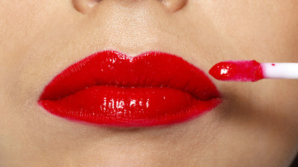 Closeup female red lips with makeup lipstick brush