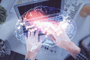 Double exposure of man's hands typing over computer keyboard and brain hologram drawing. Top view. Ai and data technology concept.