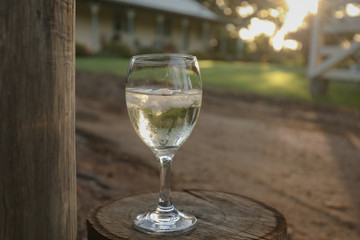 Glass of white wine on country property at sunset