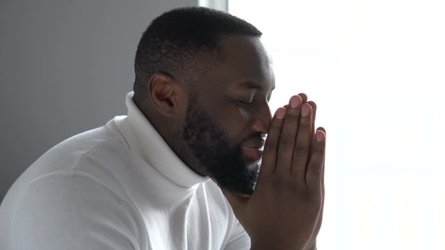 Happy african american man praying God, saying thanks for support and care