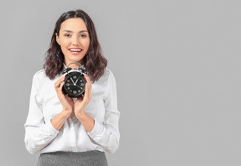 Businesswoman with alarm clock on grey background. Time management concept
