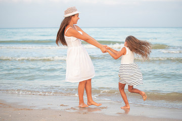 Two girls relax on the beach and walks the sea waves on a sunny summer evening during vacation.