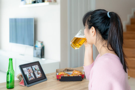 Asian Woman Virtual Happy Hour Meeting Party And Drinking Alcohol Beer Online Together With Her Friend In Video Conference With Digital Tablet For A Online Meeting In Video Call For Social Distancing.