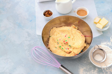 Bowl with sweet dough and products on color background