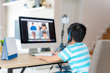 Fototapeta Asian boy student video conference e-learning with teacher and classmates on computer in living room at home. Homeschooling and distance learning ,online ,education and internet. obraz