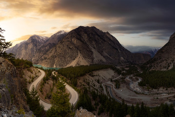 Aerial View of a Scenic Road in the Canadian Mountain Landscape during a cloudy sunset. Sky Replacement Composite. Taken in Lillooet, BC, Canada.