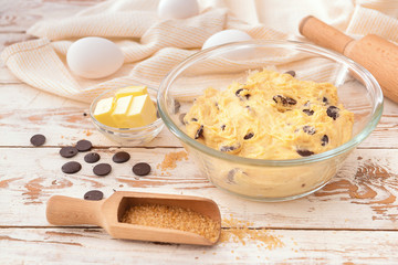 Bowl with sweet dough and products on table