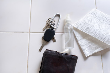 Keys, wallet and spray bottle with disinfectant on white background