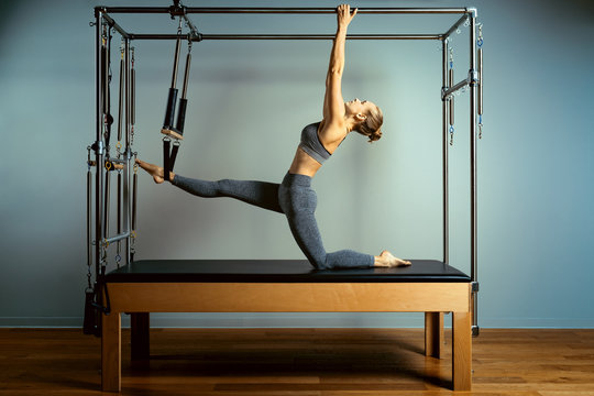Active motivated woman does exercises in bed reformer, beauty and health. Plastic, posture, smart fitness.