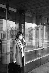 Obraz premium Young attractive caucasian businesswoman with mask and bag in front of company