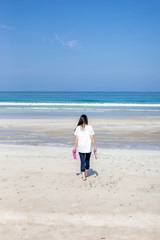 Fototapeta na wymiar 白浜ビーチを歩く女性
