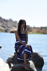 Portrait of young sexy brunette girl posing on a river beach