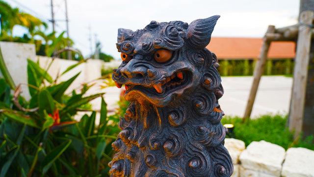 Sculpture of the mythical shisa on the roof. clay statuette on a Japanese tiled roof on background blue sky