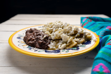 Mexican green chilaquiles with beans on white background