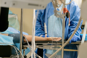 Patient on the operating table. Introduction to general anesthesia before surgery in the hospital. The doctor injects a medicine with a syringe.