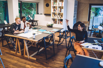 Male and female freelancers collaborating in coworking space discussing details of graphic project working remotely with creativity on web design, millennial copywriters briefing in workspace