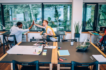 Optimistic multiethnic colleagues giving high five during work