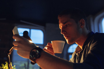 Attented. Man working in office alone during coronavirus or COVID-19 quarantine, staying to late night. Young businessman, manager doing tasks with smartphone, laptop, tablet in empty workspace.