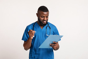 African doctor making check up, filling medical form