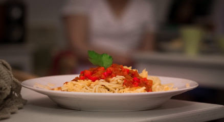 plate with spaghetti sauce and basil on white table