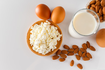 A set of healthy protein foods for a balanced diet. Cottage cheese, eggs and nuts on a white background.