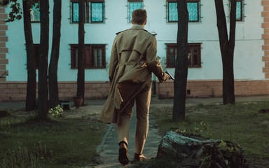 Film noir Detective man in a raincoat in a dangerous with a gun in his hand