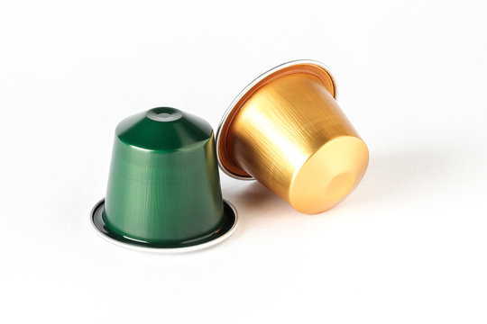 gold and green color espresso coffee capsules isolated on white background