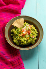Mexican guacamole with tomato and serrano pepper on turquoise background