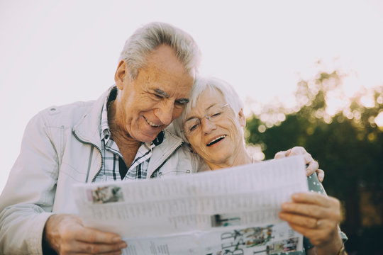 Smiling senior couple reading map while standing in city during vacation