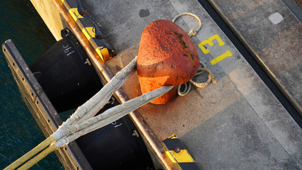 berth in the passenger port. Mooring points of the ship are fixed in the port. bright orange bollard number 13 with ship ropes. lucky bollard number - Powered by Adobe