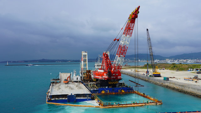 Floating crane platform with a huge bucket extracts sand from the bottom of the Pacific Ocean.
a huge crane extracts white sand from the ocean off the coast of Okinawa.