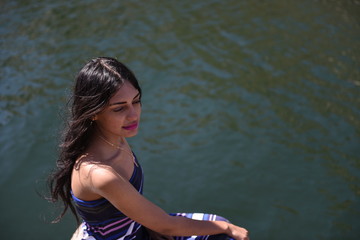 Spectacular middle eastern young woman is sitting on a rock near the river