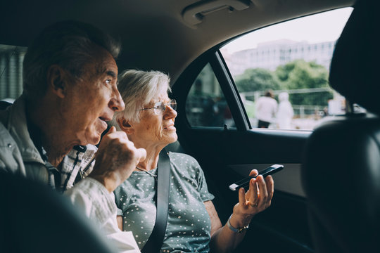 Senior woman holding mobile phone while sitting with man in car