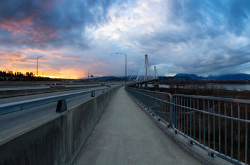 Fototapeta na wymiar Panoramic View of a path on Port Mann Bridge during vibrant Sunset. Taken in Surrey, Vancouver, British Columbia, Canada.