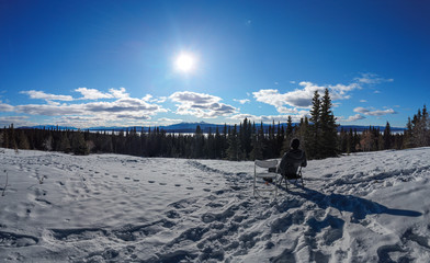 Man sitting & resting at the top of a stunning spring hike in the north of Canada on a perfect, sunny day. 